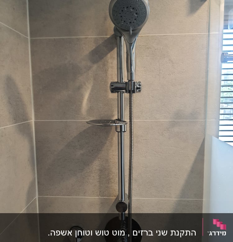 ראש מקלחת עם צינור מתכת על קיר אריחים